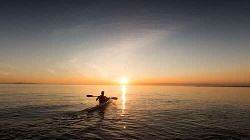 Iemand die met zonsopgang op weg gaat met zijn kano.