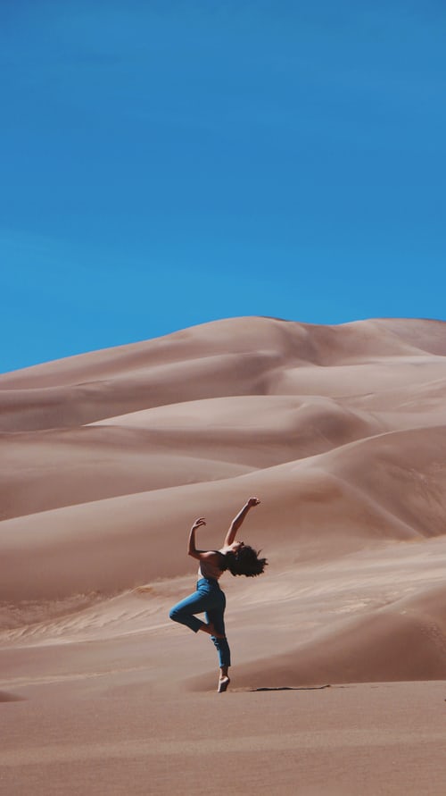 Iemand die in een woestijngebied een yogo-oefening doet.